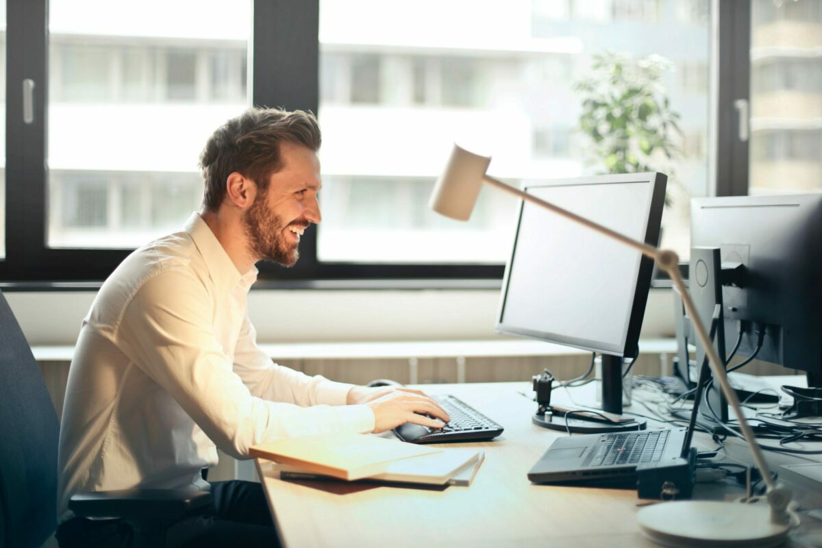 a man sitting at a desk laughing in front of a monitor